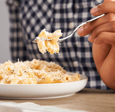  A close up of a bowl of ZENB Elbows Pasta with finely shredded cheese and ground pepper